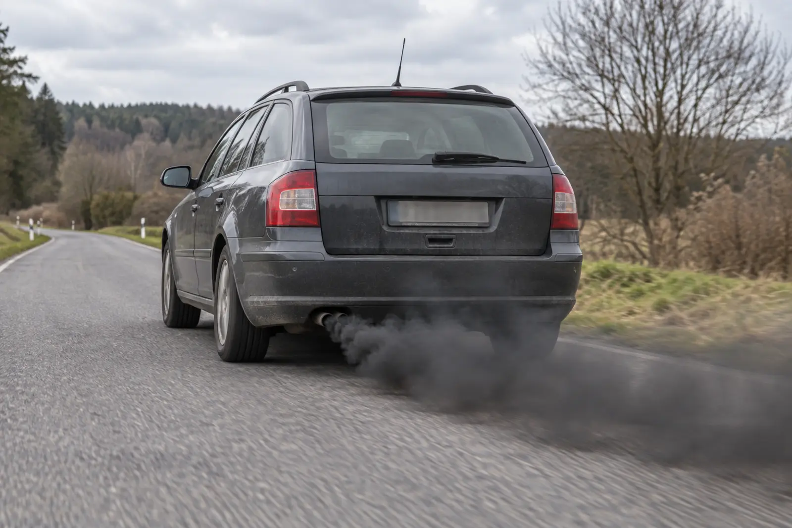 Szare kombi wypuszczające czarny dym z wydechu podczas przyspieszania
