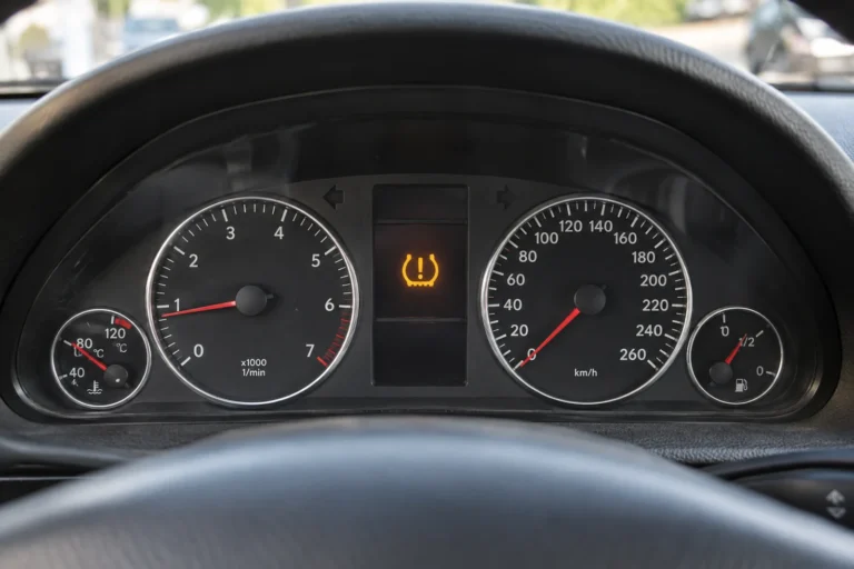 Świecąca kontrolka TPMS pomiędzy zegarami na desce rozdzielczej samochodu.